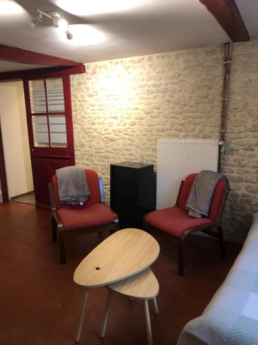 une pièce avec deux chaises, une table et un lit dans l'établissement Logement en pierres apparentes avec terrasse privative, à Giberville