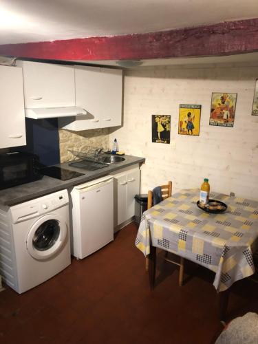 une cuisine avec une table et une machine à laver dans l'établissement Logement en pierres apparentes avec terrasse privative, à Giberville