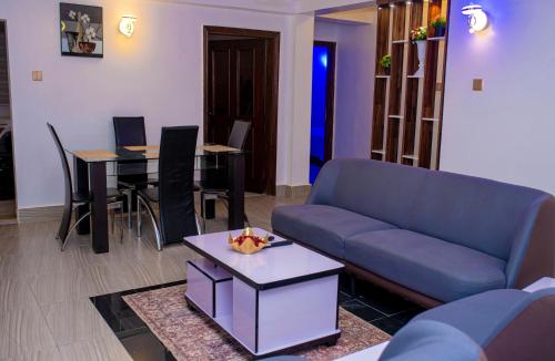 sala de estar con sofá azul y mesa en Cosystay Apartment, en Abuja