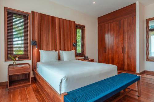 a bedroom with a large bed and a blue bench at La Coralina Island House in Bocas del Toro
