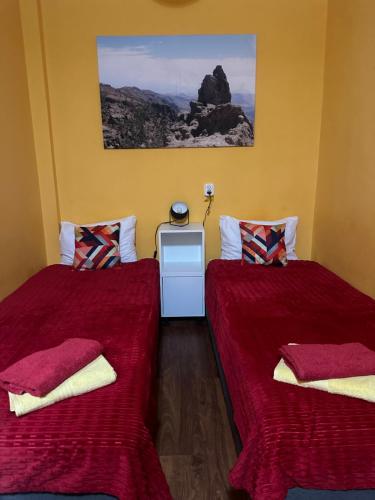 two beds in a room with red sheets and pillows at Travel House Wroclaw in Wrocław