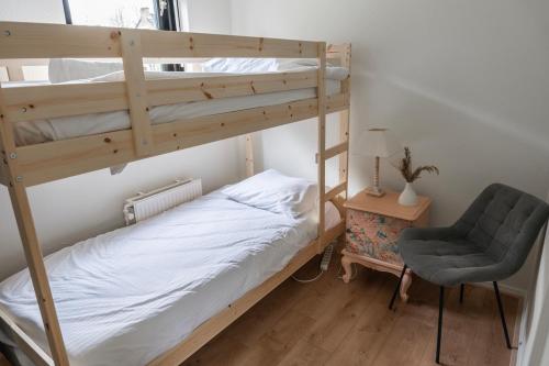 een slaapkamer met 2 stapelbedden en een stoel bij Lakeside Paradise Cozy Cottage With Hot Tub in Ewijk