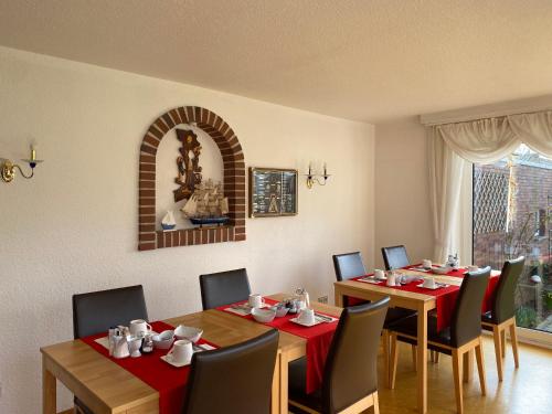 a dining room with two tables and chairs with red table runners at Pension Seehund in Norden