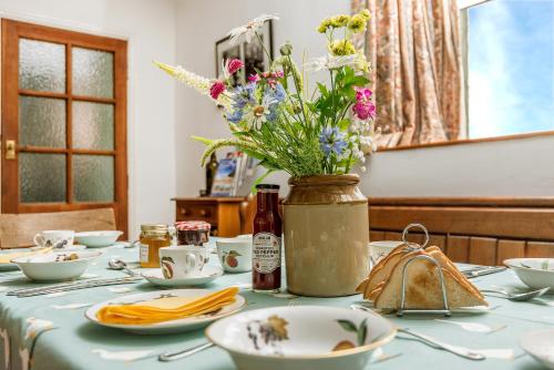 a table with a vase of flowers on it at Kidwelly Farmhouse B&B in Kidwelly