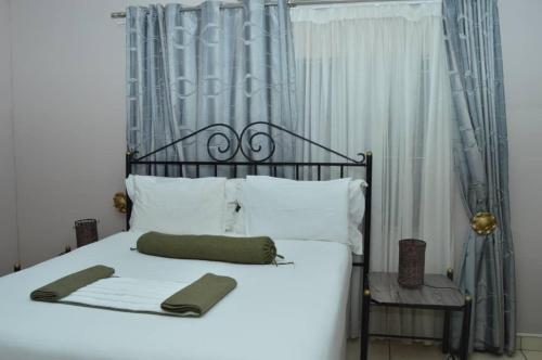 a white bed with a metal headboard and a chair at MOGONONO SELECTED SERVICE HOTEL in Palatswe