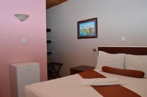 a bedroom with a bed with white sheets and a picture on the wall at MOGONONO SELECTED SERVICE HOTEL in Palatswe