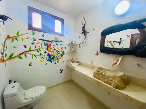 a bathroom with a toilet and a tree mural on the wall at Hotel Para Ti - Adults Only in Holbox Island
