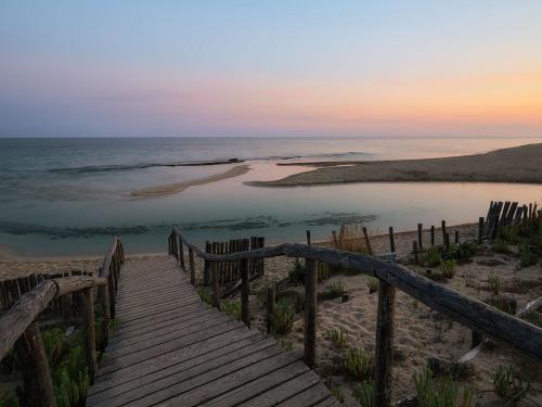 a wooden boardwalk leading to a beach at sunset at Villa d'Angela in San Pietro in Bevagna