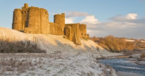 a castle sitting on top of a snow covered hill at Kidwelly Farmhouse B&B in Kidwelly
