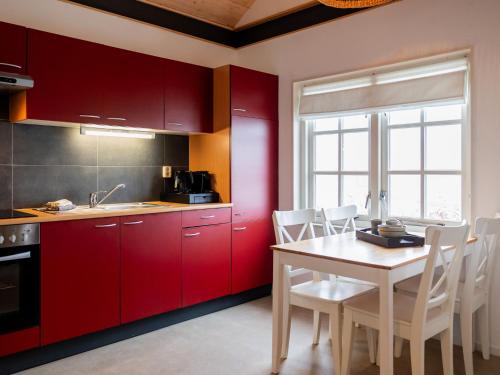 uma cozinha com armários vermelhos, uma mesa e cadeiras em Cozy chalet with palet stove em De Veenhoop