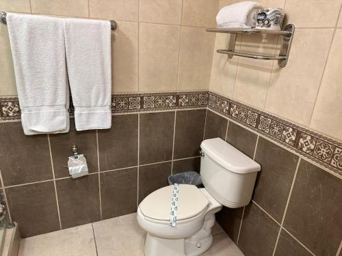 een badkamer met een wit toilet en handdoeken bij Baja Inn Hoteles Ensenada in Ensenada