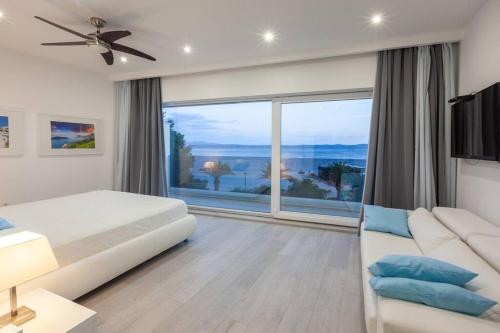 ein Schlafzimmer mit einem weißen Bett und einem großen Fenster in der Unterkunft Villa Mel I - Luxury Waterfront Villa Downtown with Pool! in Podgora