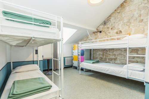 Cette chambre comprend 2 lits superposés et un mur en pierre. dans l'établissement Young and Happy Latin Quarter by Hiphophostels, à Paris