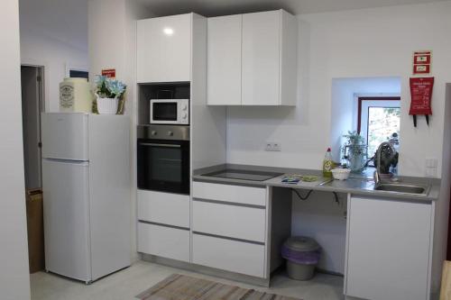 uma cozinha com armários brancos e uma bancada em Casa Manuel e Maria em Fátima
