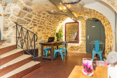 Cette chambre est dotée d'une table, de chaises et d'un mur en pierre. dans l'établissement Young and Happy Latin Quarter by Hiphophostels, à Paris