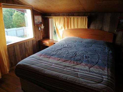 a bed in a room with a quilt on it at Cabañas Buen Recuerdo in Puyehue
