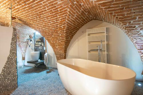 a bathroom with a large tub and a brick wall at N4U Guest House Florence in Florence