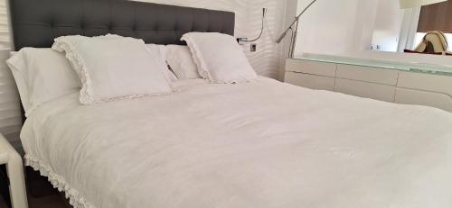 a white bed with white sheets and pillows at Villa Flavina in San Vicente del Valle