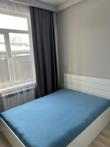 1 dormitorio con cama azul frente a una ventana en Royal House, en Almaty