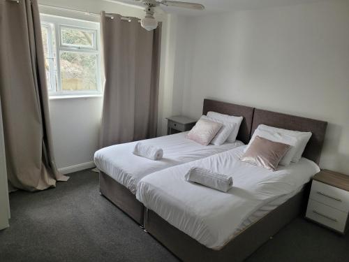 1 Schlafzimmer mit 2 Betten mit weißer Bettwäsche und rosa Kissen in der Unterkunft RentUnique Nimrod House 2 bed ample parking in Crawley