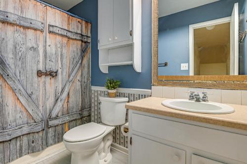 a bathroom with a wooden door and a toilet and sink at Bohemian Beach Retreat - 2 Blocks to Ocean! in Myrtle Beach