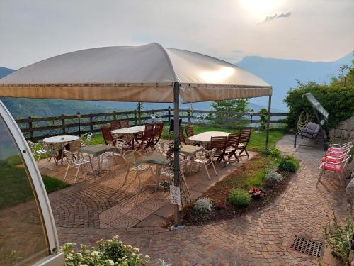 a patio with tables and chairs under an umbrella at Agritur Masi Brenta in Rovereto