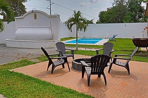 un gruppo di sedie, un tavolo e una piscina di Villa Casa Encantadora a Retalhuleu