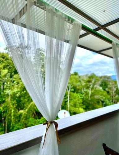 a curtain on a window with a view of trees at The Oxford Suite in Bentong