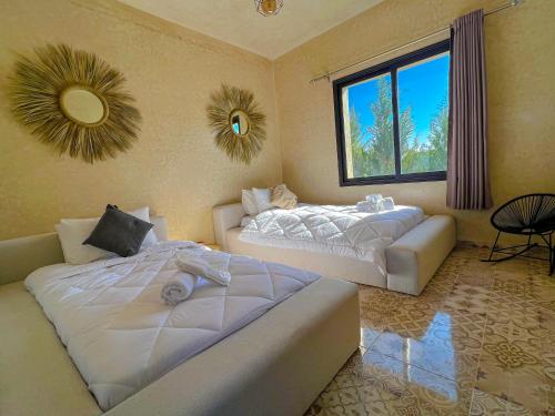 Villa OutMama charme & comfort في الصويرة: غرفة نوم بسريرين واريكة ونافذة