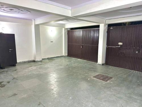 a large room with two brown doors and a concrete floor at Cozy 2bhk near Manipal Hospital Dwarka in New Delhi