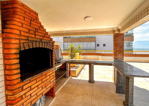 Vila BalneáriaにあるApto com WiFi a 140 metros da Praia do Caicara SPのバルコニーの真ん中にあるレンガ造りの暖炉