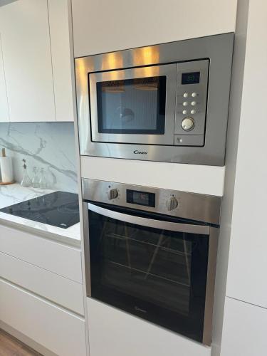 La cuisine est équipée d'un four micro-ondes au-dessus d'une cuisinière. dans l'établissement Logis doré, à Menton