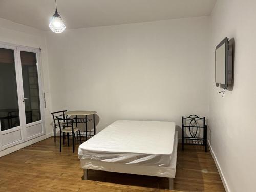 Appartement Creil Centre-ville في كريل: غرفة بيضاء بسرير وطاولة وكراسي