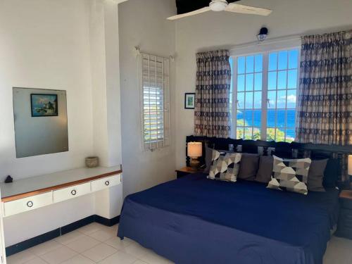 a bedroom with a blue bed with a view of the ocean at Bacolet Beach House- 5 Bedrooms/ 5 Bathrooms in Bacolet