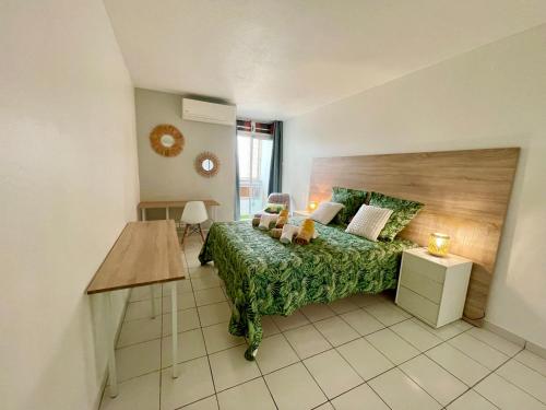 een slaapkamer met een groen bed en een tafel bij Appartement de la Mer et du Levant in Schœlcher