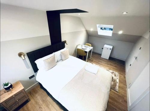Un dormitorio con una gran cama blanca y una mesa en Charming En-Suite in London en Londres
