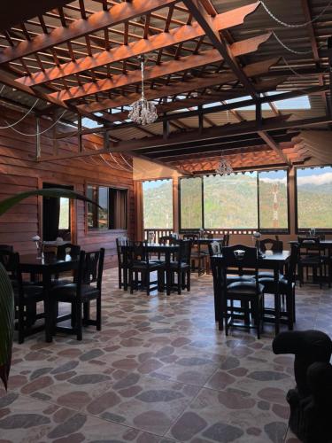 un comedor con mesas, sillas y ventanas en Dreams Lodge Orosi, en Cartago