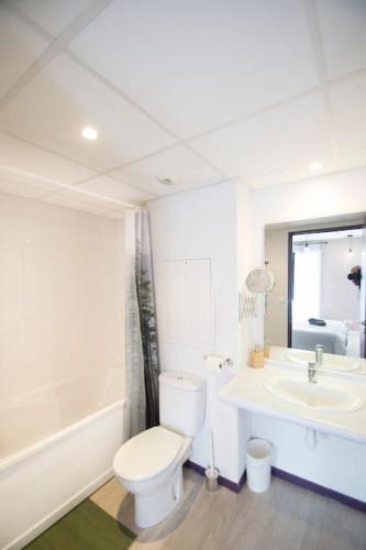une salle de bain blanche avec des toilettes et un lavabo dans l'établissement Le Panoramic - balcon - clim, à Lourdes