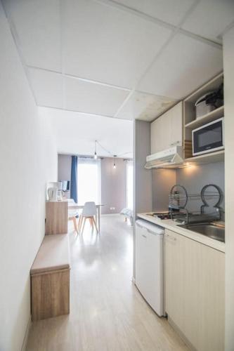 une cuisine avec des appareils électroménagers blancs et une salle à manger dans l'établissement Le Panoramic - balcon - clim, à Lourdes