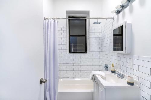 a white bathroom with a tub and a sink at 91-1D 3BR 2baths Duplex with a Private Back yard - GYM in New York