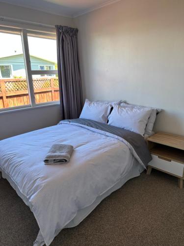 a bedroom with a white bed with a window at Hilltop Cottage in Taupo
