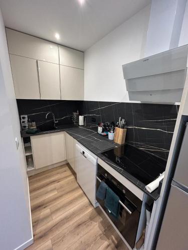 une cuisine avec des armoires blanches et des comptoirs noirs dans l'établissement Welcome appartement neuf mars 2024, à Gretz-Armainvilliers