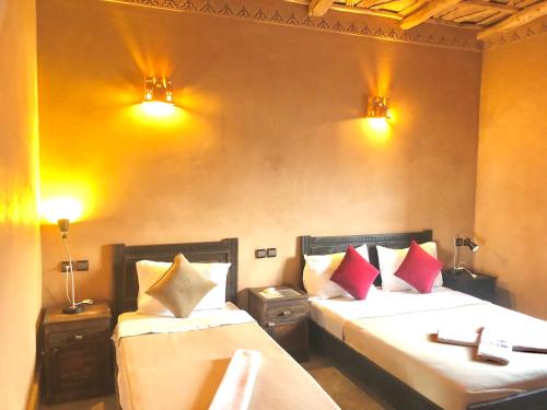 a bedroom with two beds and two lights on the wall at Kasbah Ennakb in Nkob