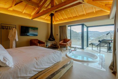 a bedroom with a large bed and a tub at Dajas Douro Valley - Exclusive Villas in Sande