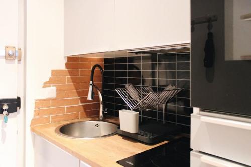 a kitchen counter with a sink and a brick wall at Sunny - Studio confortable près de la Tour Eiffel in Paris