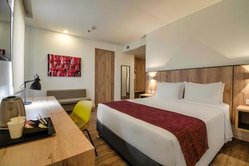 a hotel room with a large bed and a desk at Hotel Distrito ZF in Bogotá