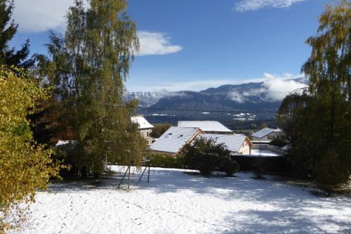 un patio cubierto de nieve con casas y montañas al fondo en Chalet avec grand jardin en Chartreuse Alpes, en Miribel-les-Échelles