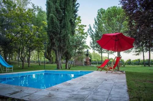 una sombrilla roja y sillas junto a la piscina en Cabaña Finca Lujan en Ciudad Lujan de Cuyo