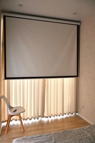 um grande ecrã de projecção numa parede com uma cadeira em Домик 1 Kok Tobe Village em Almaty