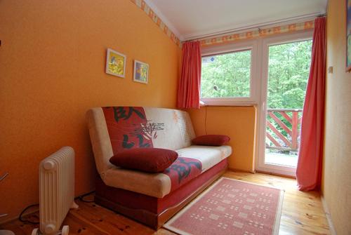 a living room with a couch and a window at Domek Leśny in Poddąbie